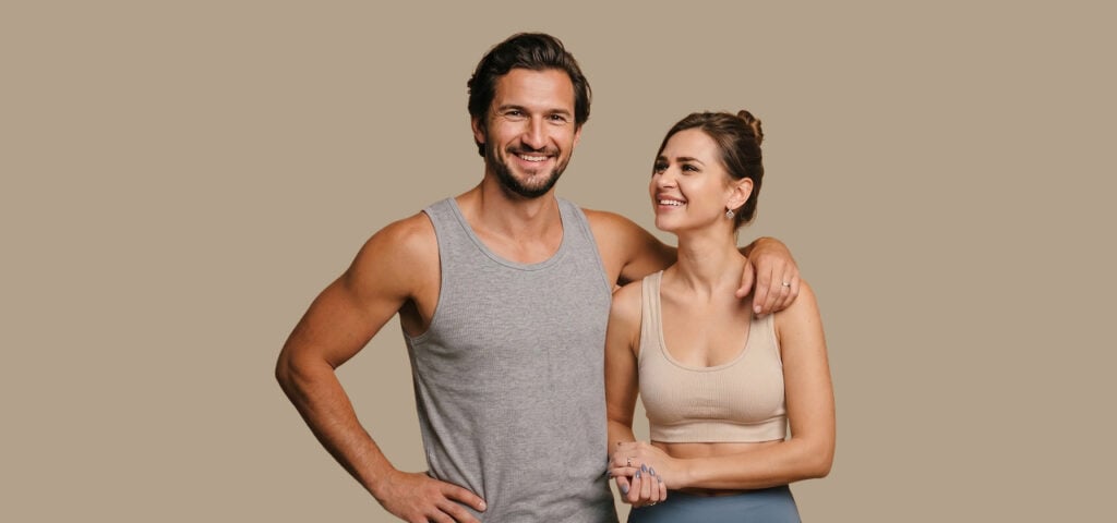 A smiling man and woman in athletic wear, representing the energy and vitality peptide therapy patients pursue.