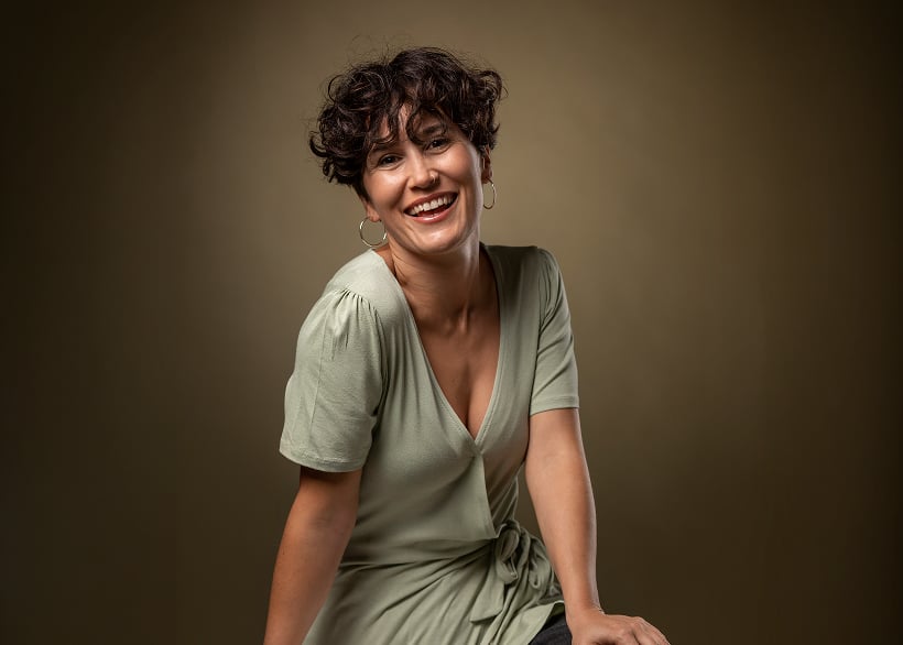 A confident, smiling woman in a sage-green dress, representing the vitality and well-being women pursue through bioidentical hormone replacement therapy.